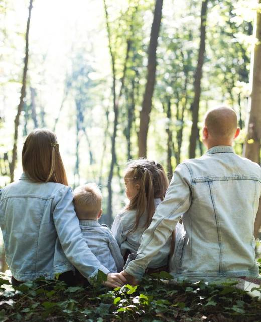 man and woman holding hands together with boy and girl looking at green trees during day